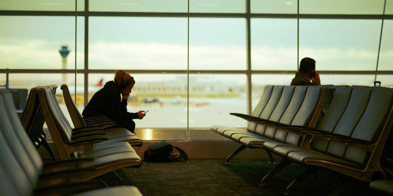 Two people sit in an airport waiting area