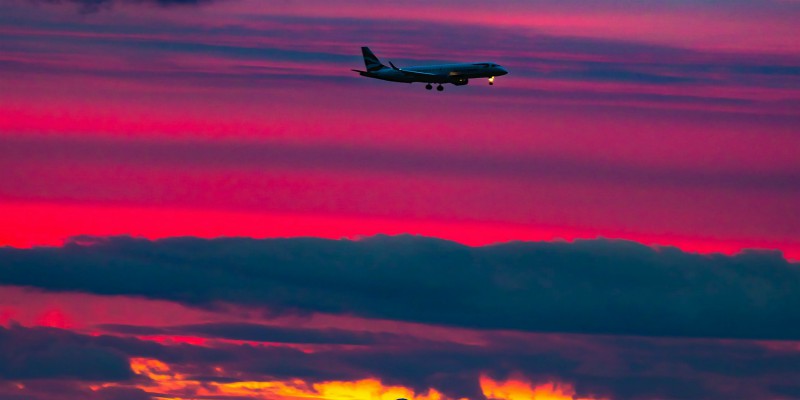 A plane takes off against a colourful sky