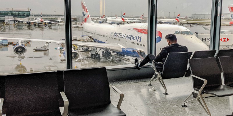 Man relaxes in an airport terminal look out of the window at planes parked